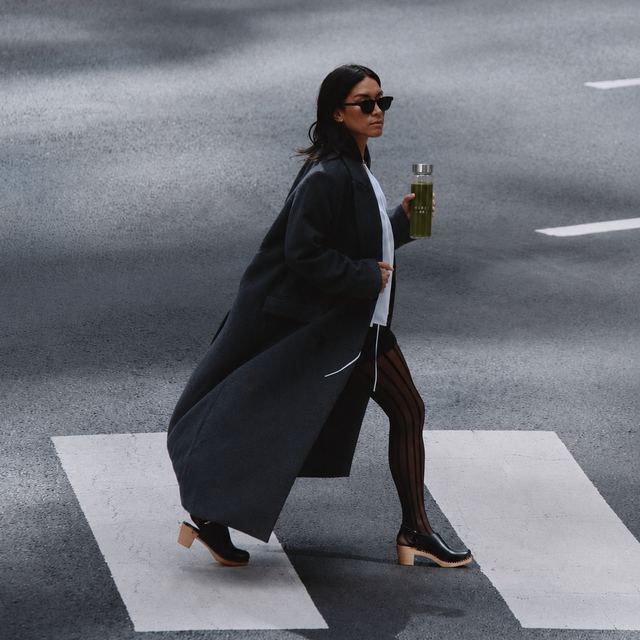 Woman carrying a KIREI bottle across a city crosswalk
